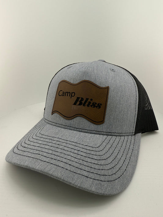 Baseball hat with Camp Bliss logo in leatherette on the front. Front of hat is Grey back of hat is black mesh. 