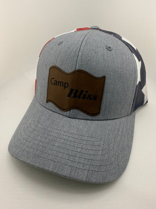 Baseball hat with Camp Bliss logo in leatherette on the front. Front of hat is grey and back of hat is american flag mesh. 