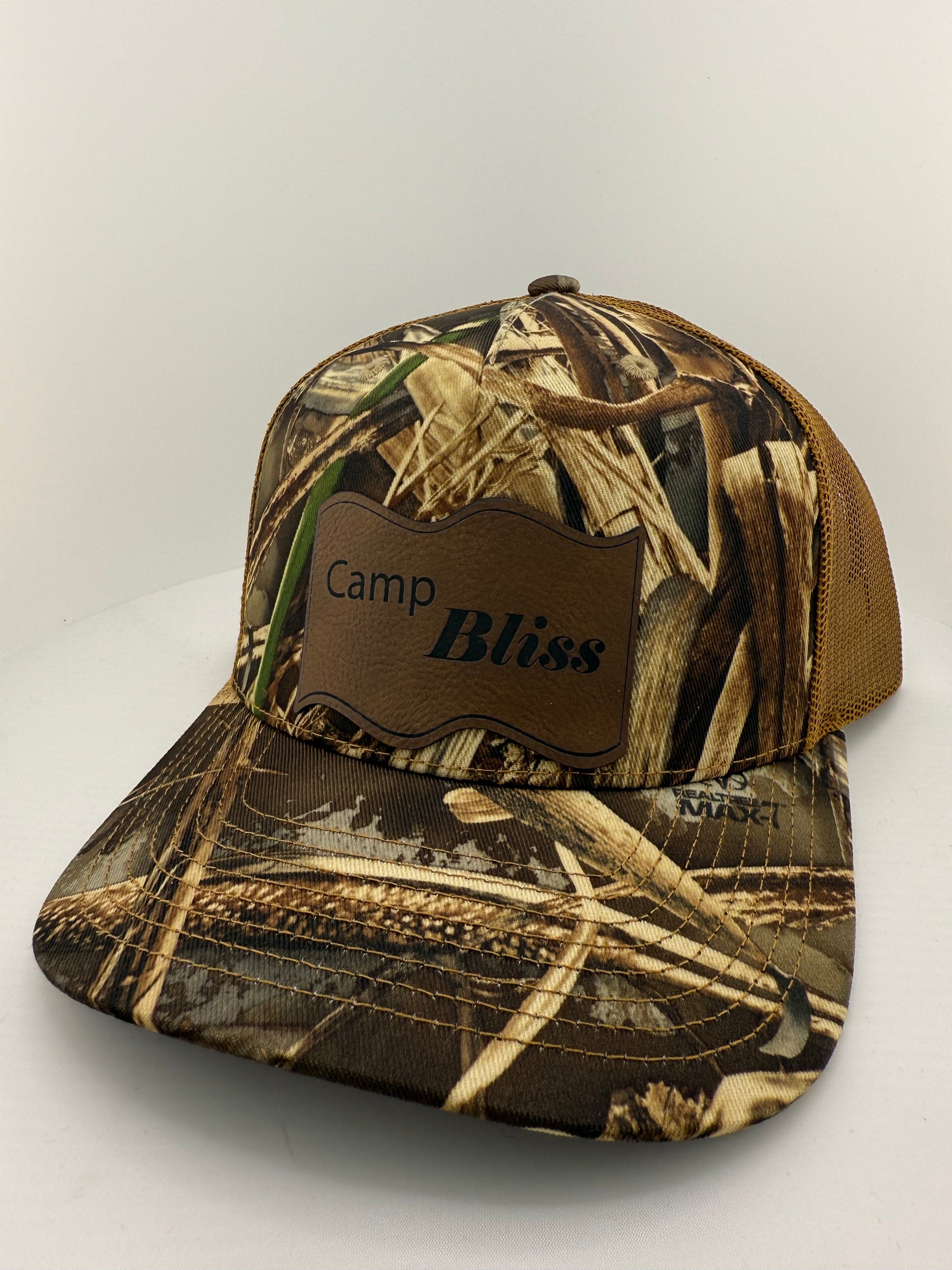 Baseball hat with Camp Bliss logo in leatherette on the front. Front of hat is realtree camo and back of hat is Brown mesh